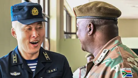 SA National Defence Force A naval officer from China and South Africa military officer - both in their respective uniforms - greet each other.