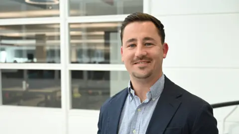 Reed Talent Solutions Phil Bearpark wearing a blue suit jacket smiles and looks into the camera.