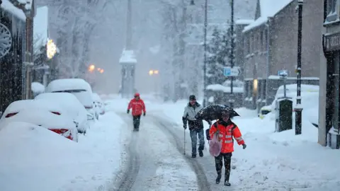 Getty Images People walk in the roads during a snowfall in Huntly, Scotland.